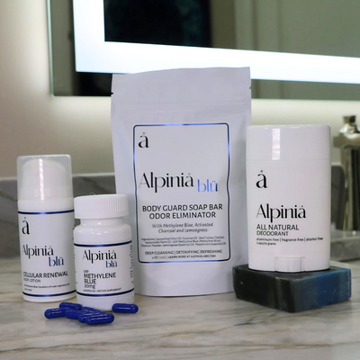 Full body wellness kit including white deodorant, soap, blue Methylene Blue capsules, and body lotion on a marble surface